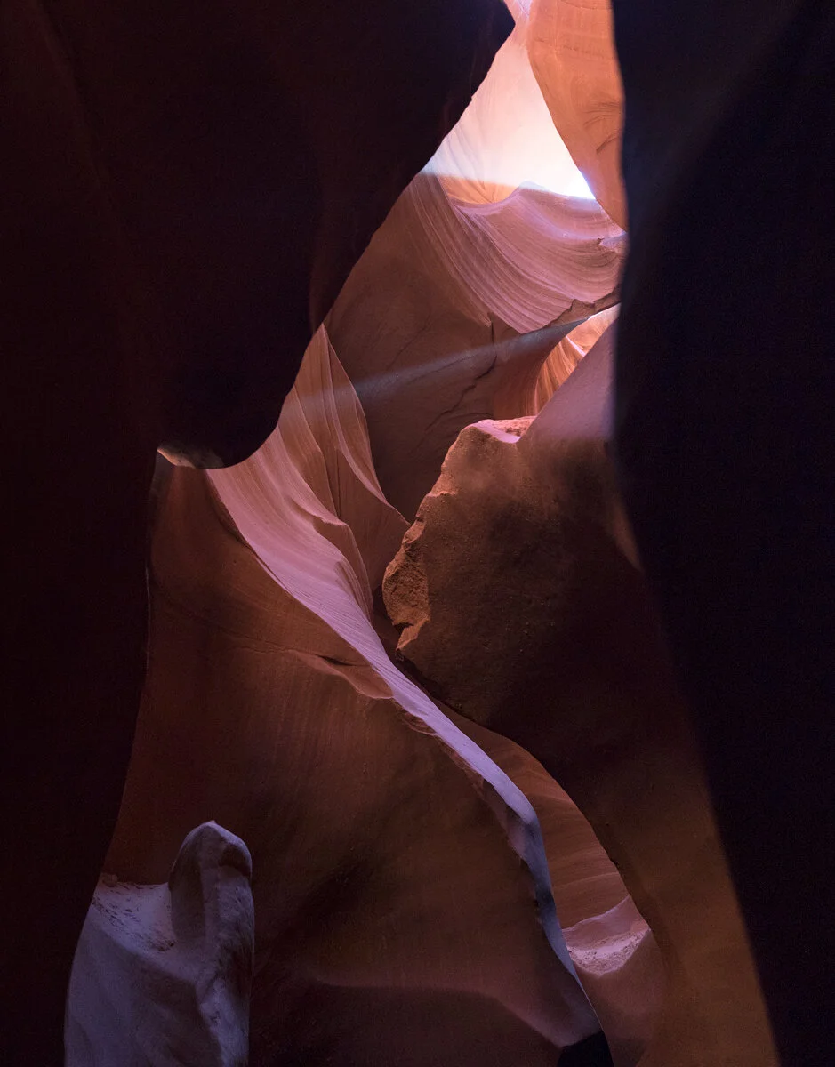Light beam illuminating swirling sandstone walls in Antelope Canyon