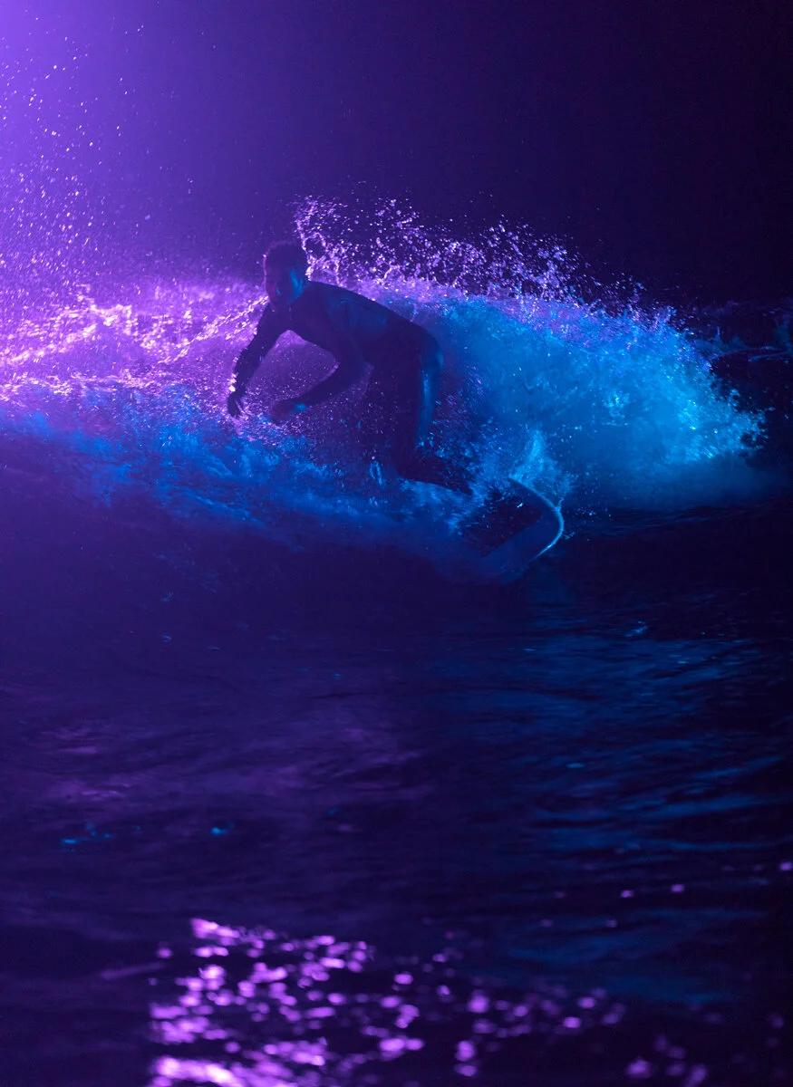 River surfer riding a lit-up wave at night in Bend, Oregon
