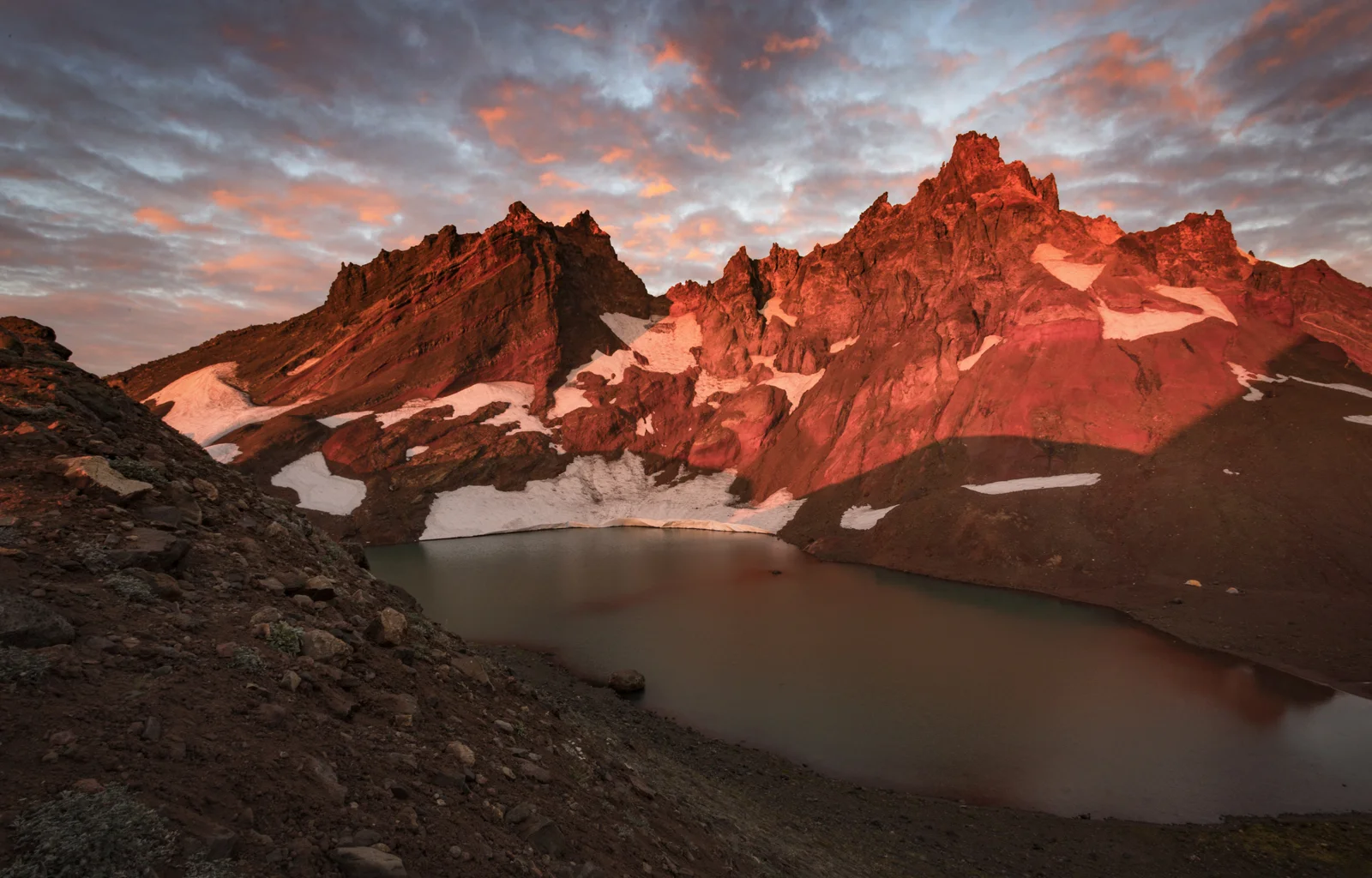 Broken Top's jagged peaks reflected in an alpine lake at sunset