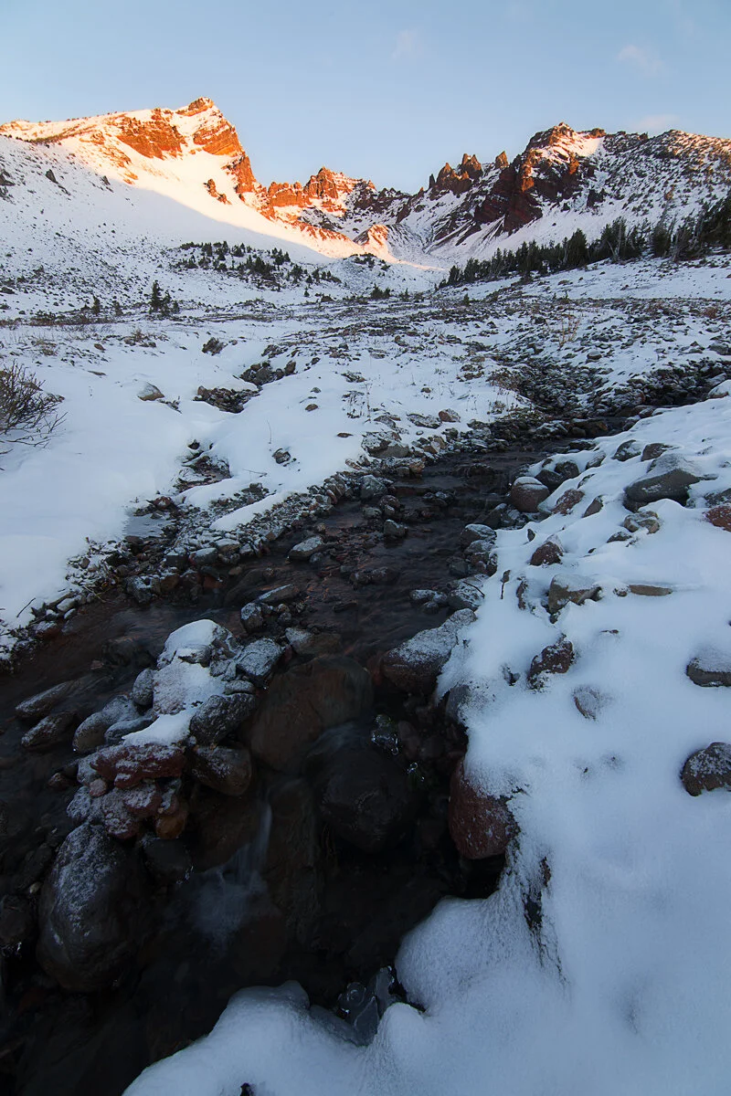 Broken Top's snowy peaks catching alpenglow above a frozen creek