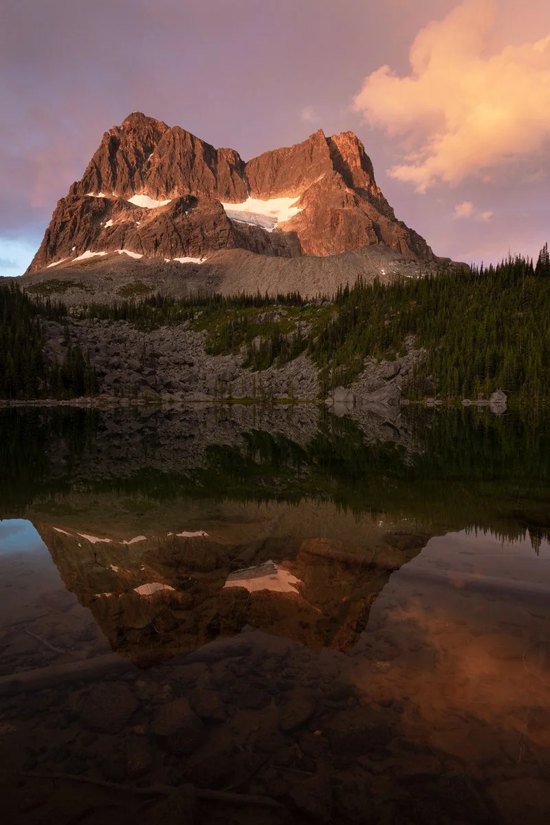Jagged Canadian Rockies peak reflected in a calm alpine lake at dusk