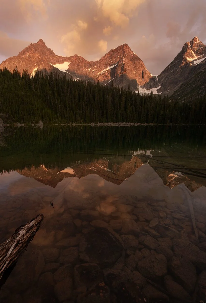 Sunset light on Canadian Rockies peaks reflected in a clear alpine lake