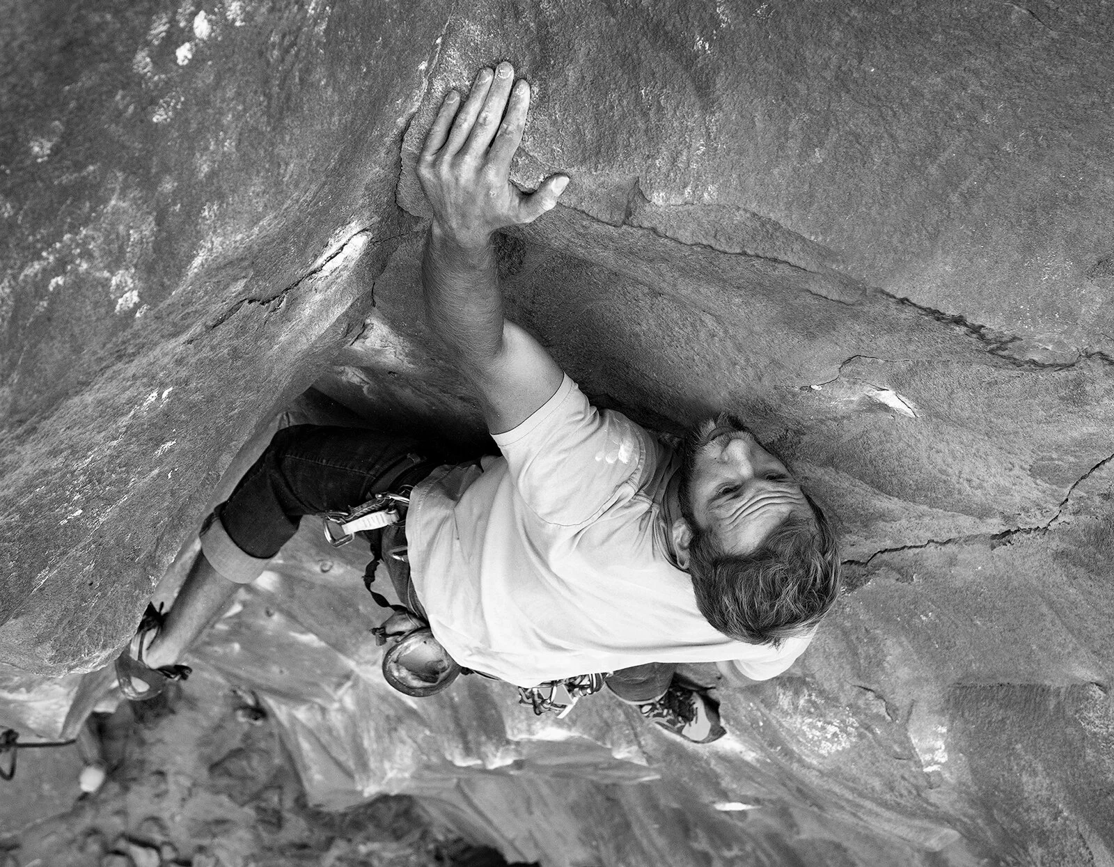 Black-and-white close-up of a rock climber reaching for a hold at Smith Rock