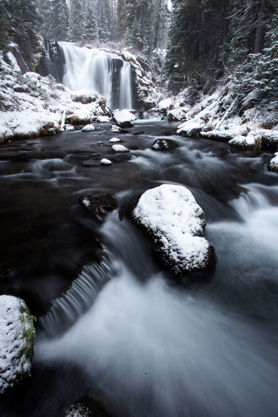 Fall Creek Falls cascading past snow-dusted boulders in a winter forest