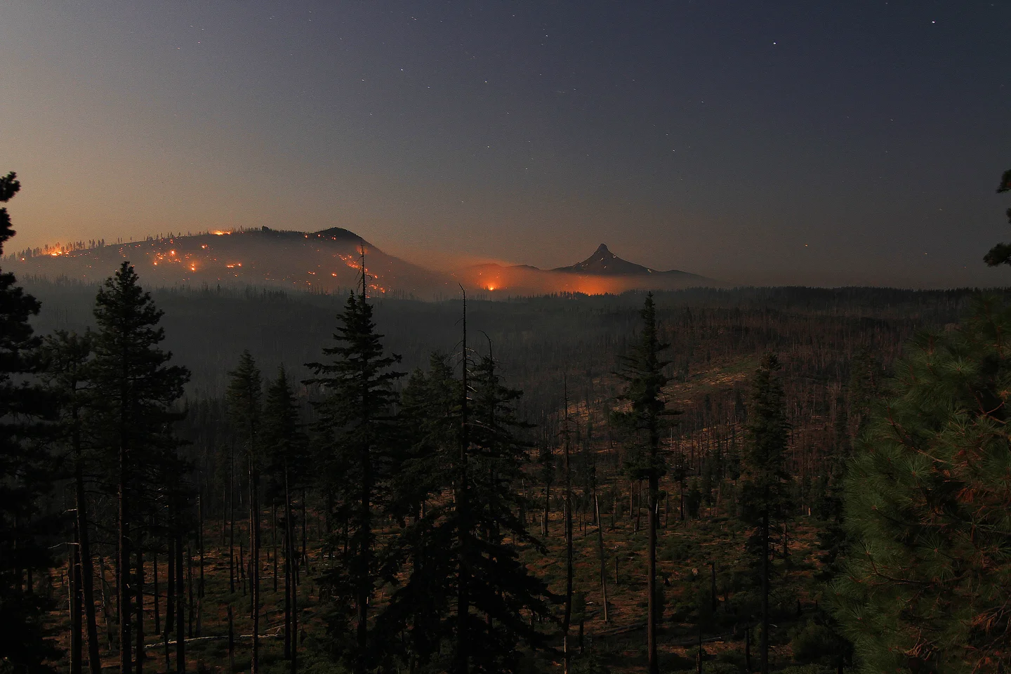 Wildfire glow lighting up hillsides below Mount Washington at night