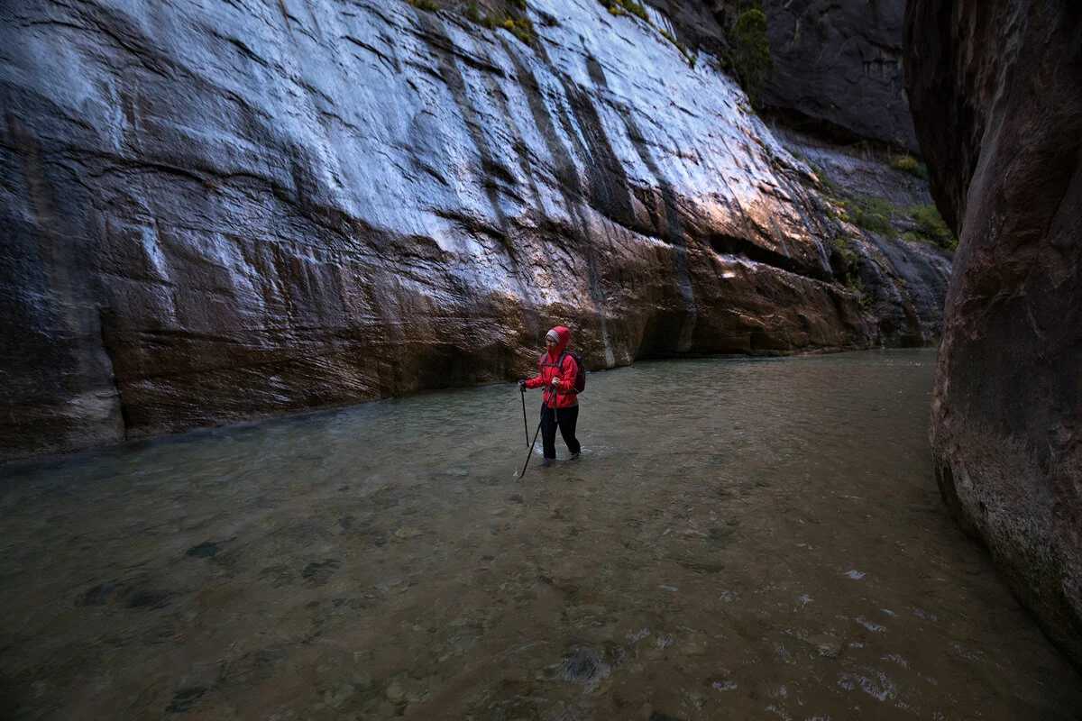 Hiker wading through the Virgin River in Zion Narrows canyon