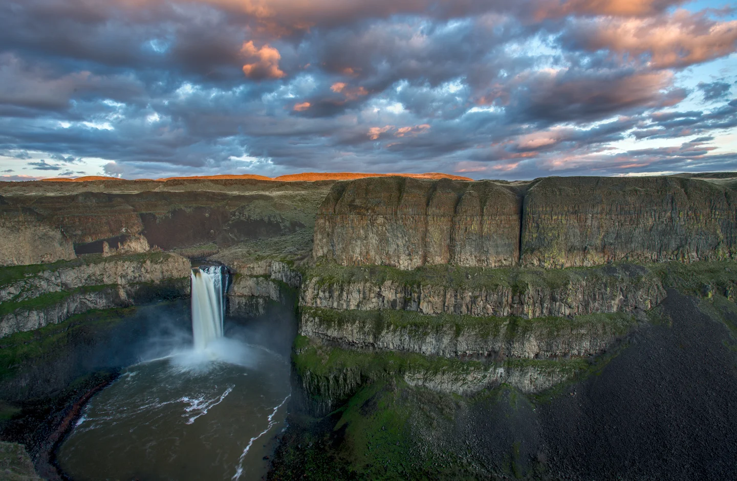 Palouse Falls plunging into a basalt canyon under dramatic clouds