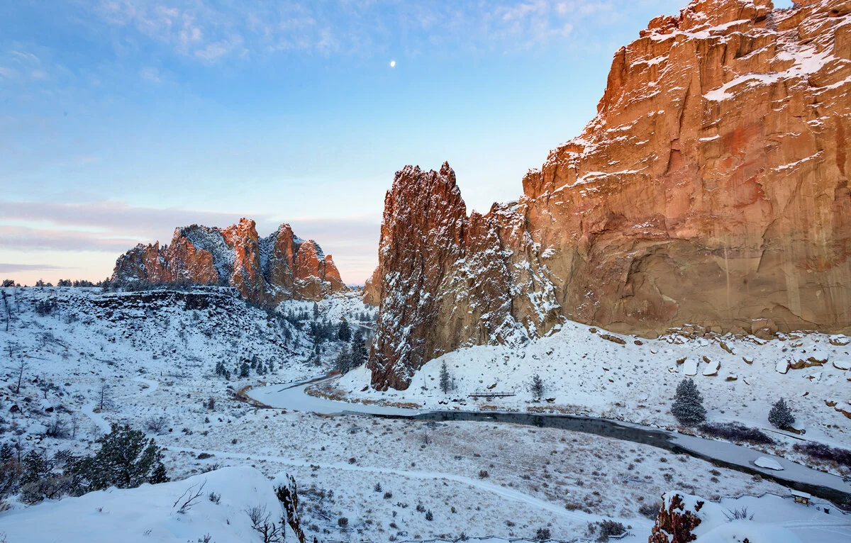 Smith Rock's snow-dusted spires with a daytime moon in winter