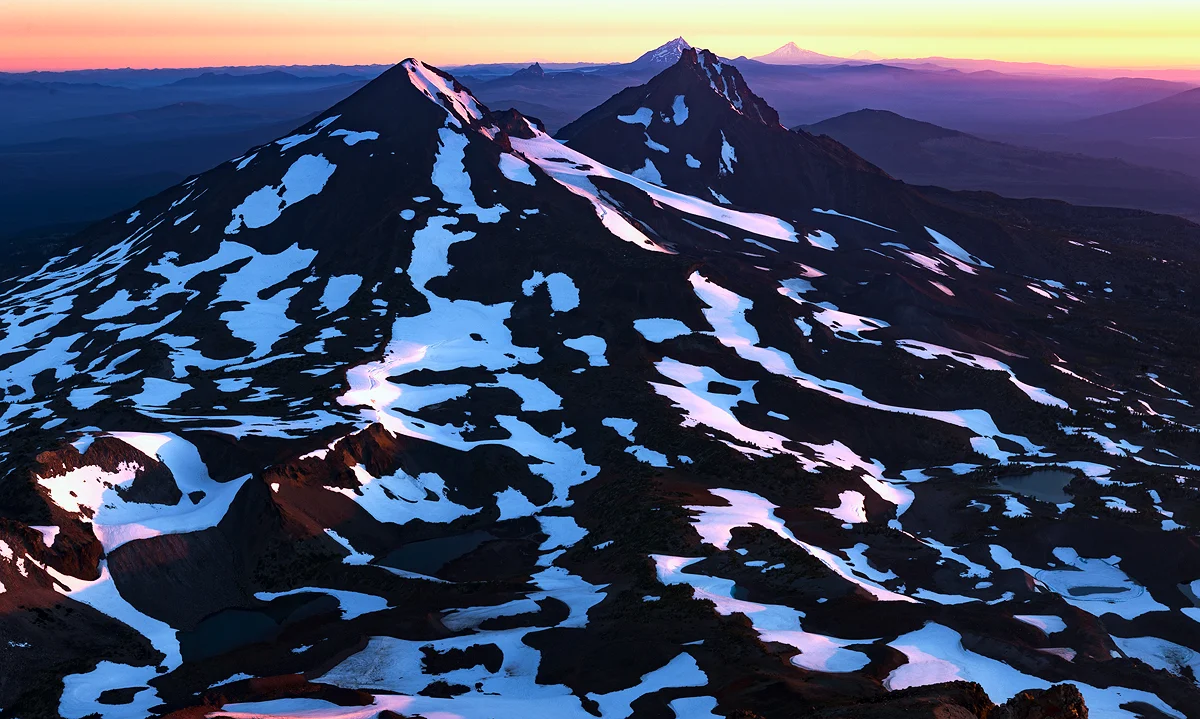 Snow-patched Cascade peaks viewed from South Sister's summit at sunrise