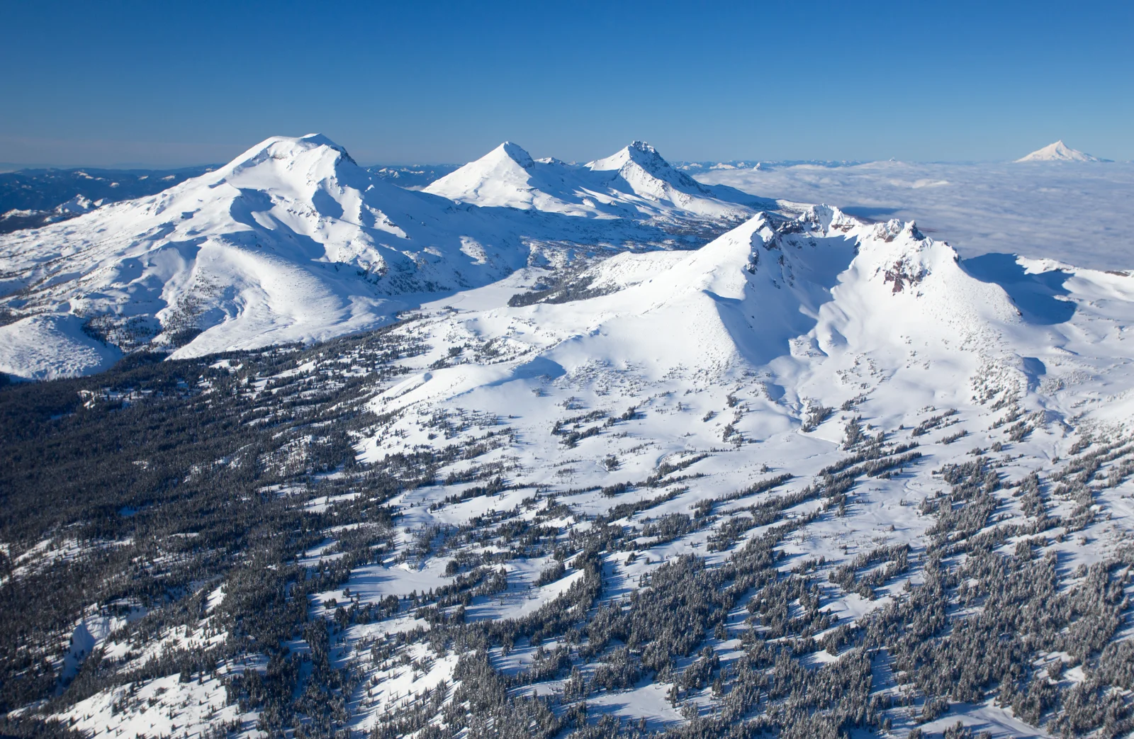Aerial winter view of the Three Sisters and Broken Top with Mount Hood on the horizon
