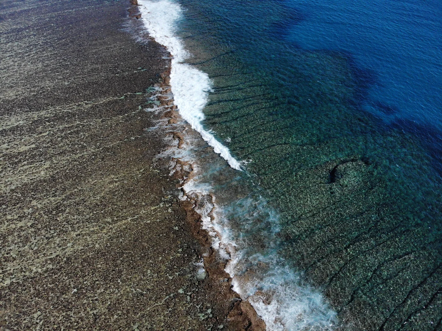 Aerial view of a wave breaking over a rocky reef ledge in Western Australia